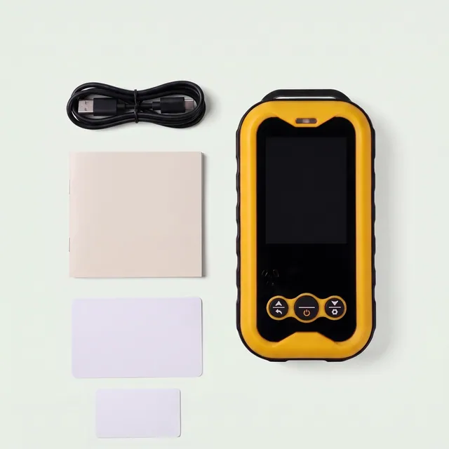 Flat lay of the yellow Geiger counter, a coiled USB-C cable, a small booklet and two plain cards